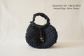 Borsa nera rotonda su sfondo Maison du Crochet